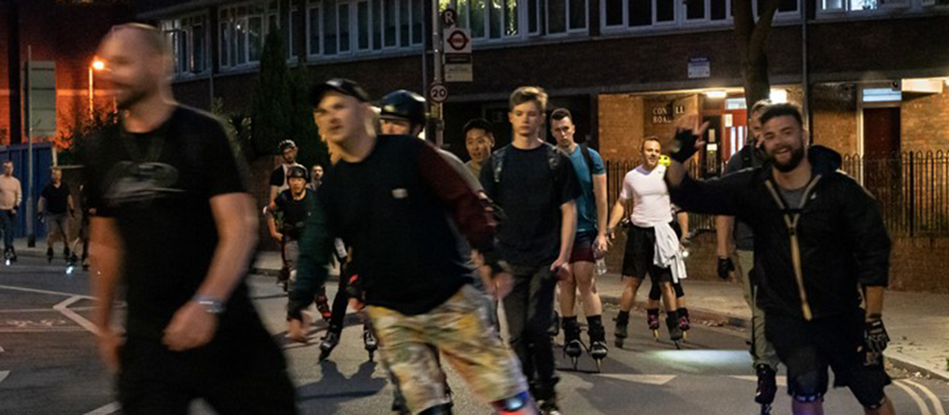 Night time photograph showing people roller blading along a street, having fun